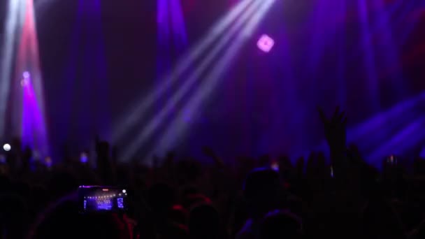 スローモーションで撮影されたバックビューライト付きの音楽ライブイベントで手を上げている人 — ストック動画