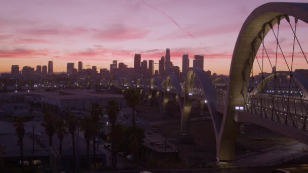 位于加利福尼亚州洛杉矶的第六街高楼大厦 黄昏时分 天空一片粉色 远处耸立着摩天大楼 该桥于2022年重建并向公众开放 看到车辆流量 — 图库视频影像