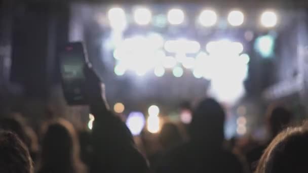 ライブやコンサートの際に携帯電話を手に持っていることのぼやけた景色 舞台や照明を背景に — ストック動画