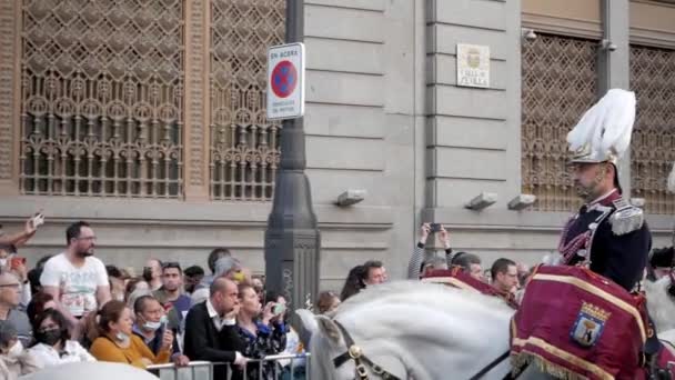 パンニングショット 乗馬ガードは スペインのマドリードでの聖週間のお祝いの間に良い金曜日の宗教行列を開きます 周りの群衆 白い馬 ヘルメットと制服を着た警備員 — ストック動画