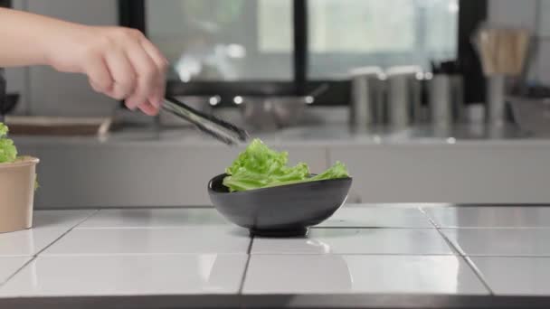 Hand Legt Frische Grüne Salatblätter Eine Keramikschale Mit Einer Zange — Stockvideo