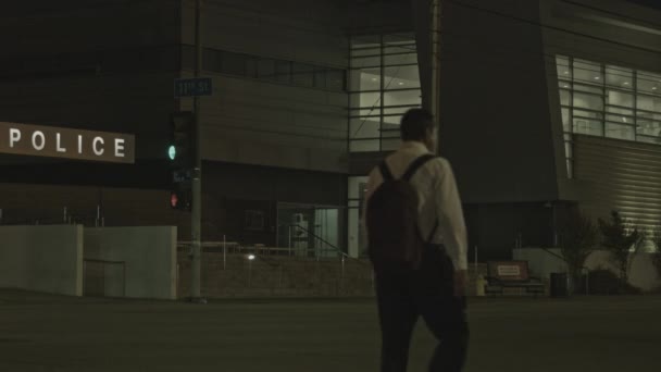 通りを夜歩く人々の静的なショット 警察署は遠くに見えます — ストック動画