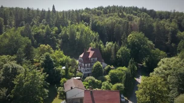 ドイツ ヘッセの晴れた夏の日に鬱蒼とした森の中にある古い半木造の建物の空中写真 — ストック動画