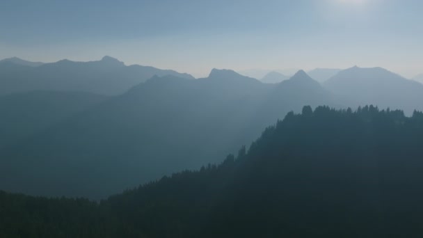 在喀斯喀特山脉向日出飞去的空中镜头 山脊和树木在薄雾中耸立着 — 图库视频影像