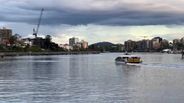昆士兰州布里斯班市 厚重的乌云掠过天空 城市猫号渡轮在布里斯班河上巡航 沿河一带有住宅大楼 天气预报称天气恶劣 — 图库视频影像