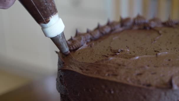 アイシングバッグとチップでケーキを飾る 隔離されたクローズアップチョコレートケーキシリーズ — ストック動画