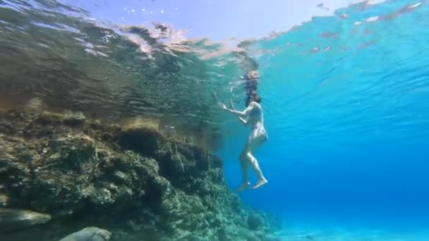 一个年轻的女孩在水面上游泳 从水下俯瞰 在度假时潜水 — 图库视频影像