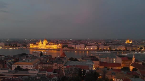 ブダとペストの間に位置ドナウ川で照らされたハンガリー議会の着実な空中ビュー — ストック動画