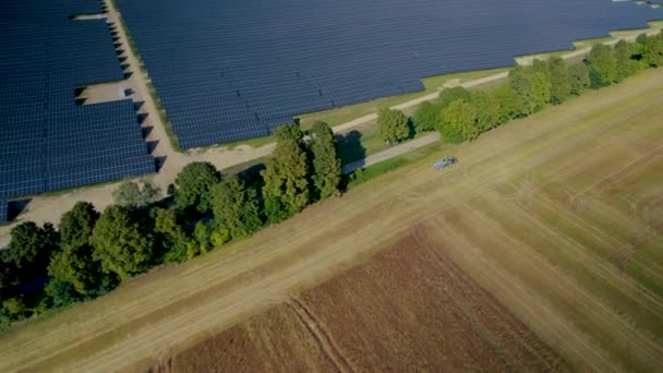 Luftaufnahme Einer Großflächigen Solarmodulfarm Mit Vorbeifahrendem Traktor Pan Right Kippt — Stockvideo