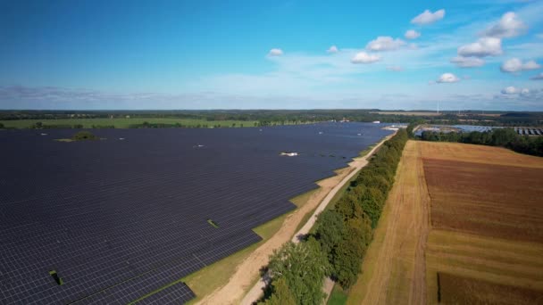 農地と巨大な太陽光パネルアレイの境界に降下空中ビューは きれいな緑の再生可能エネルギーを生成します — ストック動画