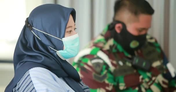 マスクをした年配の女性が病院に列に並び インドネシアのパンデミック時にウイルスワクチンを接種する — ストック動画