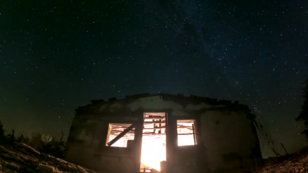 日落后 一座废弃的棚屋内的照明是前景 星辰在船舱上空旋转 而北极星在中间时差 — 图库视频影像