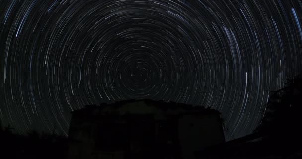 ゴーストタウンの放棄された衝撃のシルエットは 北極星の北極星が真上にあり 地球が回転する際に円を形成する星の軌跡 長時間の露出時間の経過 — ストック動画