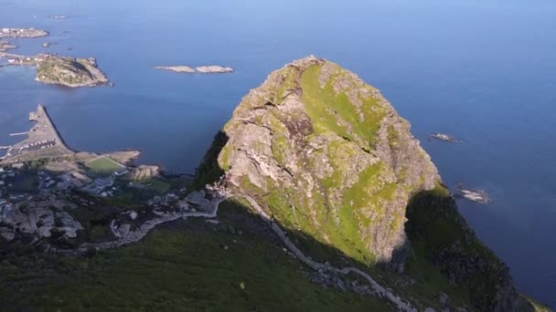 ノルウェーの島の村を見下ろす日当たりの良いReinebringenのハイカーの空中 — ストック動画