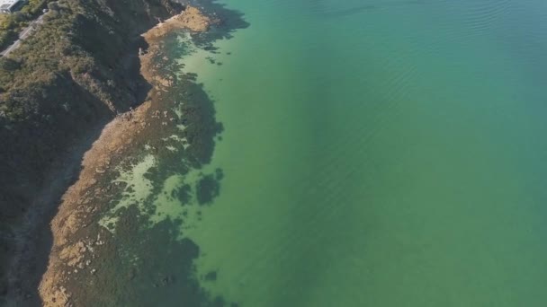 海辺の町の崖の端に澄んだ青い水の上に空中ドローン — ストック動画