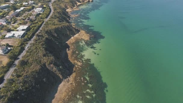 澄んだ青い水を運転する車と道路で崖の町の無人航空機の静的なショット — ストック動画