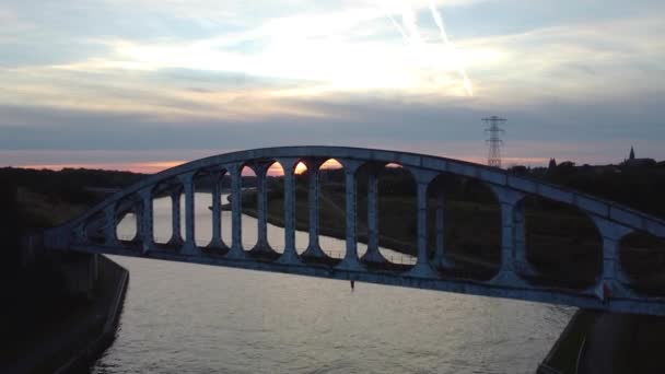 日没時に川を渡って鋼アーチ鉄道橋 空中上昇ビュー — ストック動画