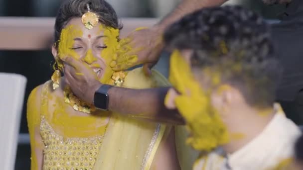 喜庆的年轻印度新娘和新郎的脸被应用与明亮的黄色粉刷在哈尔迪函数在他们的婚礼周 选择性聚焦 慢动作 — 图库视频影像