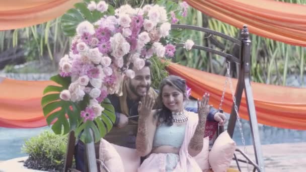 美丽的印度订婚夫妇向图片 婚礼上 新娘穿着装饰的胳膊坐在新娘的摇椅上 新郎站在她身后 — 图库视频影像