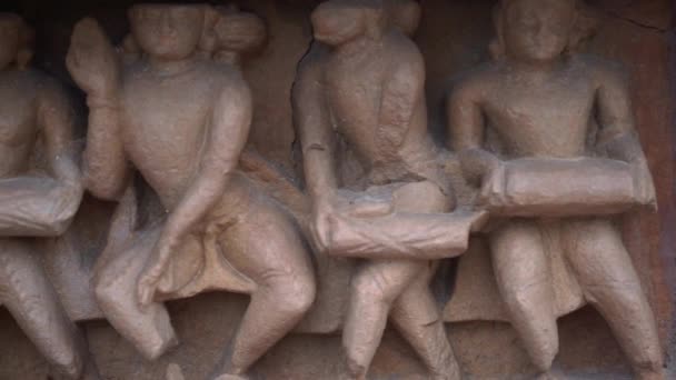 インドのマディヤ プラデーシュ州カジュラホ寺院で古代の人々の暮らしを描いた古い石壁の彫刻 閉じて 左にスライド — ストック動画