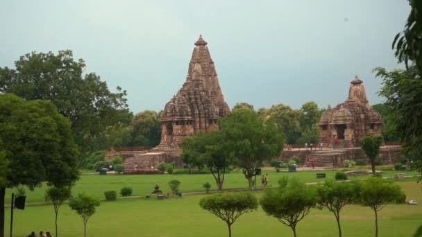 隣接する2つのヒンドゥー教寺院 デヴィ ジャグダンビとカンダリーヤ マハーデフ寺院の眺めインドのマハーディヤ プラデーシュ州カジュラホの美しい緑の風景 ワイドショット — ストック動画