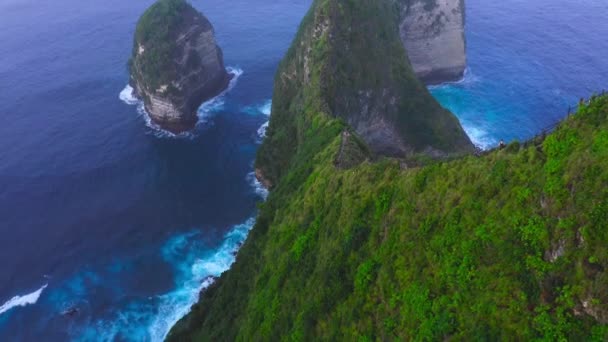沿着陡峭的绿色悬崖峭壁上升的空中延伸到海里 徒步旅行者爬上山顶 Nusa Penida — 图库视频影像