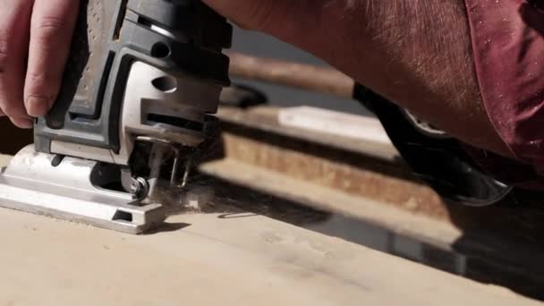 ジグソーを使って木の板から形を切り取る男性労働者 Cloup — ストック動画