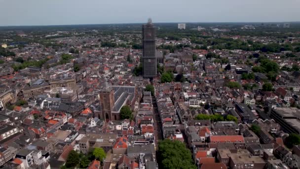オランダの都市中心部の足場にあるDe Dom中世の大聖堂の塔のパノラマの空中アプローチ青い空の日の出と地平線のオレンジ色の輝きに対する街並みにそびえる — ストック動画