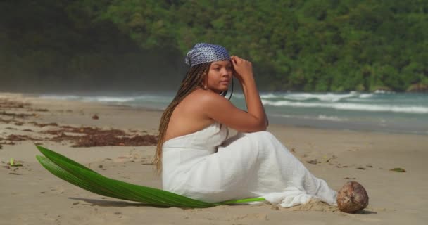 在热带岛屿的海滩上 一名身穿海滩礼服的年轻女子坐在海滩上 动作十分缓慢 — 图库视频影像
