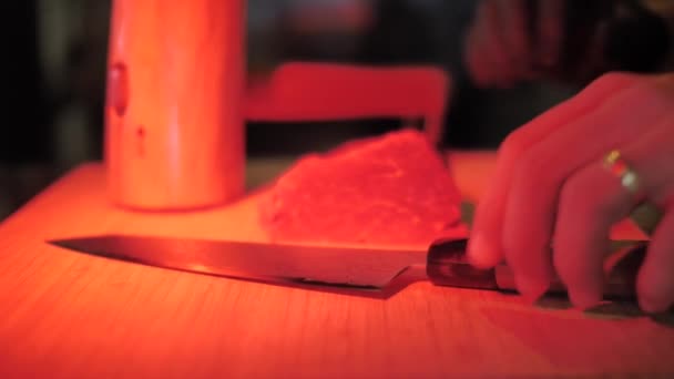 无法辨认的厨师用一块生牛肉切牛排 用红光调关闭 — 图库视频影像