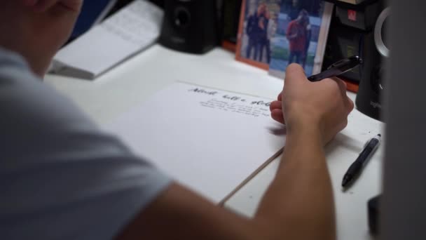 一个拿着钢笔和白纸做作业的男生写了一首情诗 选择性焦点 — 图库视频影像