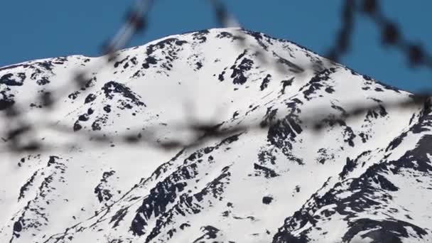 ヒンドゥー教のクシュ山脈の雪に覆われた山のピーク 有刺鉄線フェンスの後ろからのテレフォトビュー ラックフォーカスショット — ストック動画