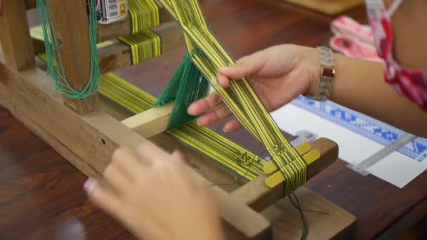 伝統的なアジアのパターンを作成するために織りプロセス中に通過する緑の糸の織機を可能にするために糸を分離するために使用される指 肩の上にクローズアップとして撮影 — ストック動画