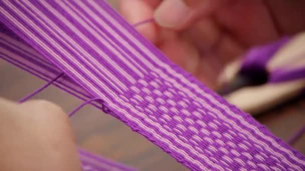 伝統的なアジアの手で織られたベルトのパターンを作成するために 紫色と白の糸を弦と押す指は 極端なクローズアップとして撮影 — ストック動画