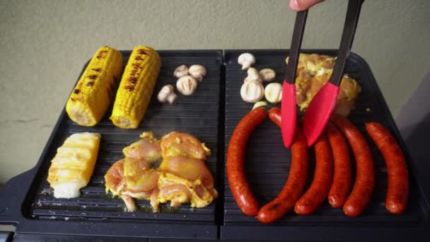 用硅胶钳在烤架上烤热狗香肠的人 高角度 — 图库视频影像