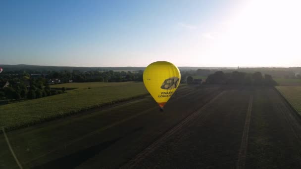 オランダの田園地帯を飛ぶ明るい黄色の熱気球の空中朝の日の出ビュー トラッキングショット — ストック動画