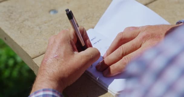 Αριστερόχειρας Γράφει Στο Σημειωματάριό Του Ένα Στυλό Στο Ξύλινο Τραπέζι — Αρχείο Βίντεο