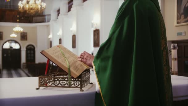 緑の衣を着た司祭は 宗教的なミサを行う前に カトリック教会内の聖書の経典を読む — ストック動画