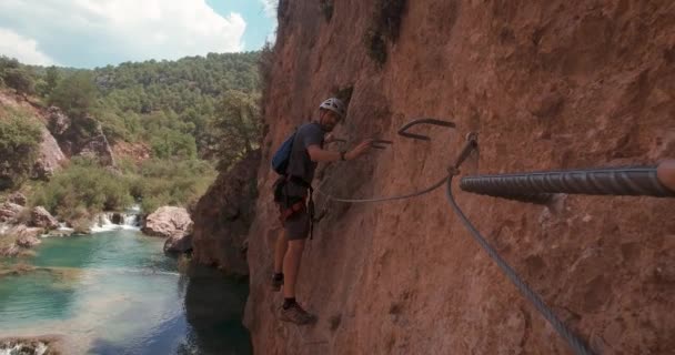 在美丽的河流和瀑布之上的费拉塔大街岩壁上 Pov动作凸轮的年轻登山者 — 图库视频影像