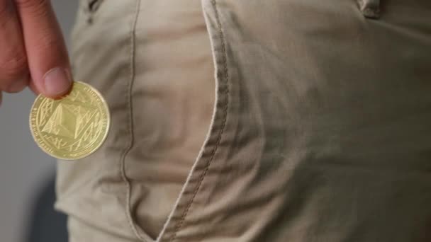 黄金のエテリアムコインは 人間の手でポケットに入れられています 静的接近 — ストック動画