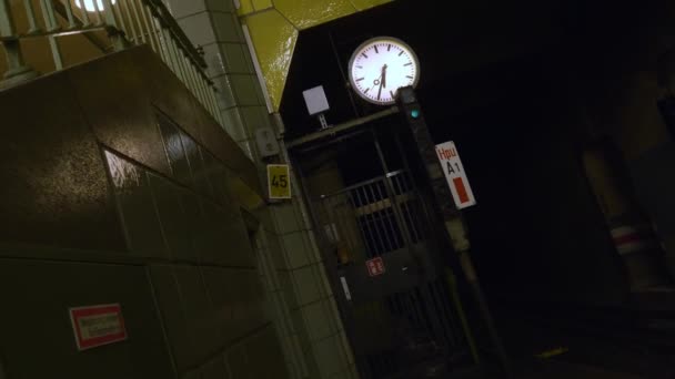 タイヤの壁と地下鉄の駅で時計の超現実的なドーリー後方回転ショットを開催 気味の悪いと距離 — ストック動画