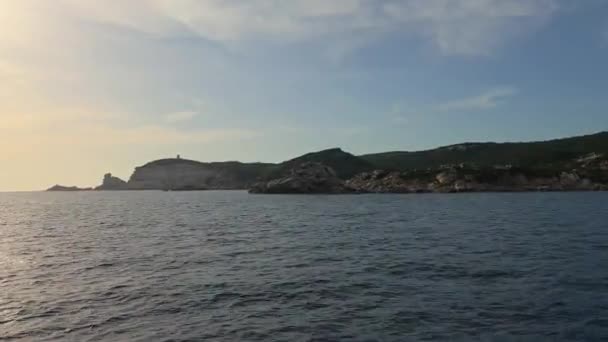 コルシカ島の崖やフランスのカポ ペルタサト灯台に向かって波打つ海の水を航行する帆船の弓の視点 50Fps — ストック動画