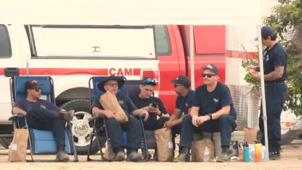 Пожежники Роблять Перерву Сидячи Під Маркою Розмовляючи Один Одним — стокове відео