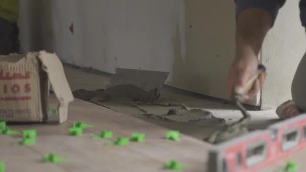 用水泥大肠搅拌和铺在地板上放置瓷砖时 工人手部的固定镜头 — 图库视频影像