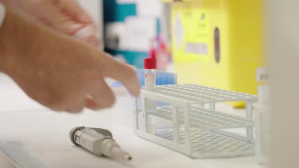 臨床研究者の閉鎖血液管を試験管内に入れる実験室のベンチにラック — ストック動画