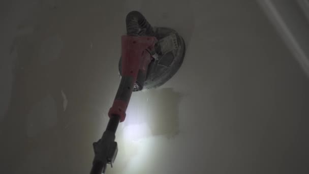 仕上げのための白い壁に対して使用されている電気サンダーの動的ハンドヘルドショット — ストック動画