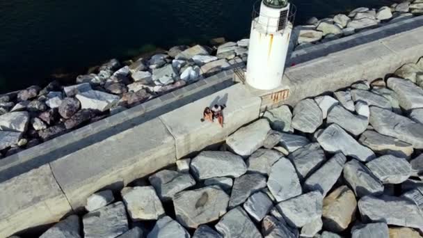 カモリ海岸 青い海 ジェノヴァの古い灯台の横に座っているカップル — ストック動画
