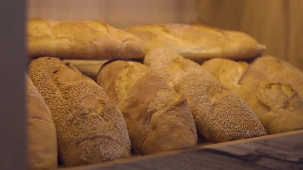 焼きたての黄金のパン パンの背景でいっぱいのベーカリーショップの棚 — ストック動画