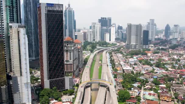 マレーシアのクアラルンプールのスカイライン 高層ビルと住宅ビルを隔てる高速道路上のドローン — ストック動画