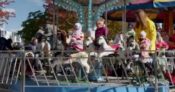メリーゴーランドで馬を楽しんでいる母親と子供の静的なスローモーションショット — ストック動画